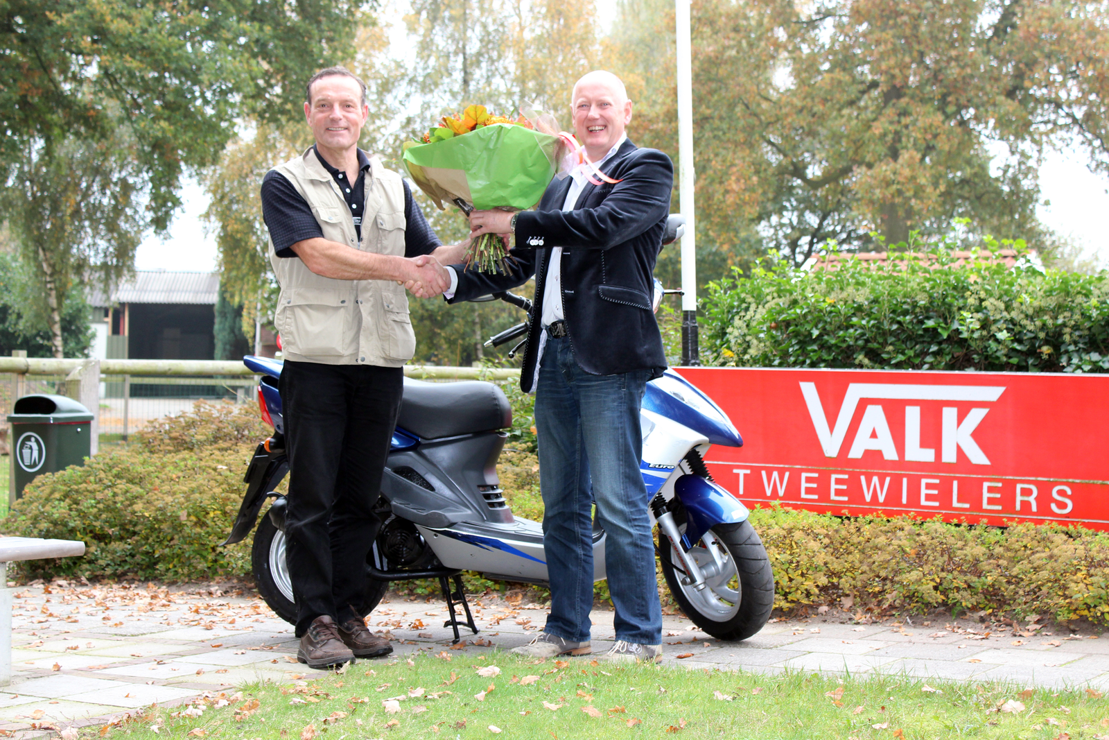 Wim Disselhorst uit Nijverdal (links) heeft een ton gereden met zijn SYM scooter. Dat verdient een bloemetje.