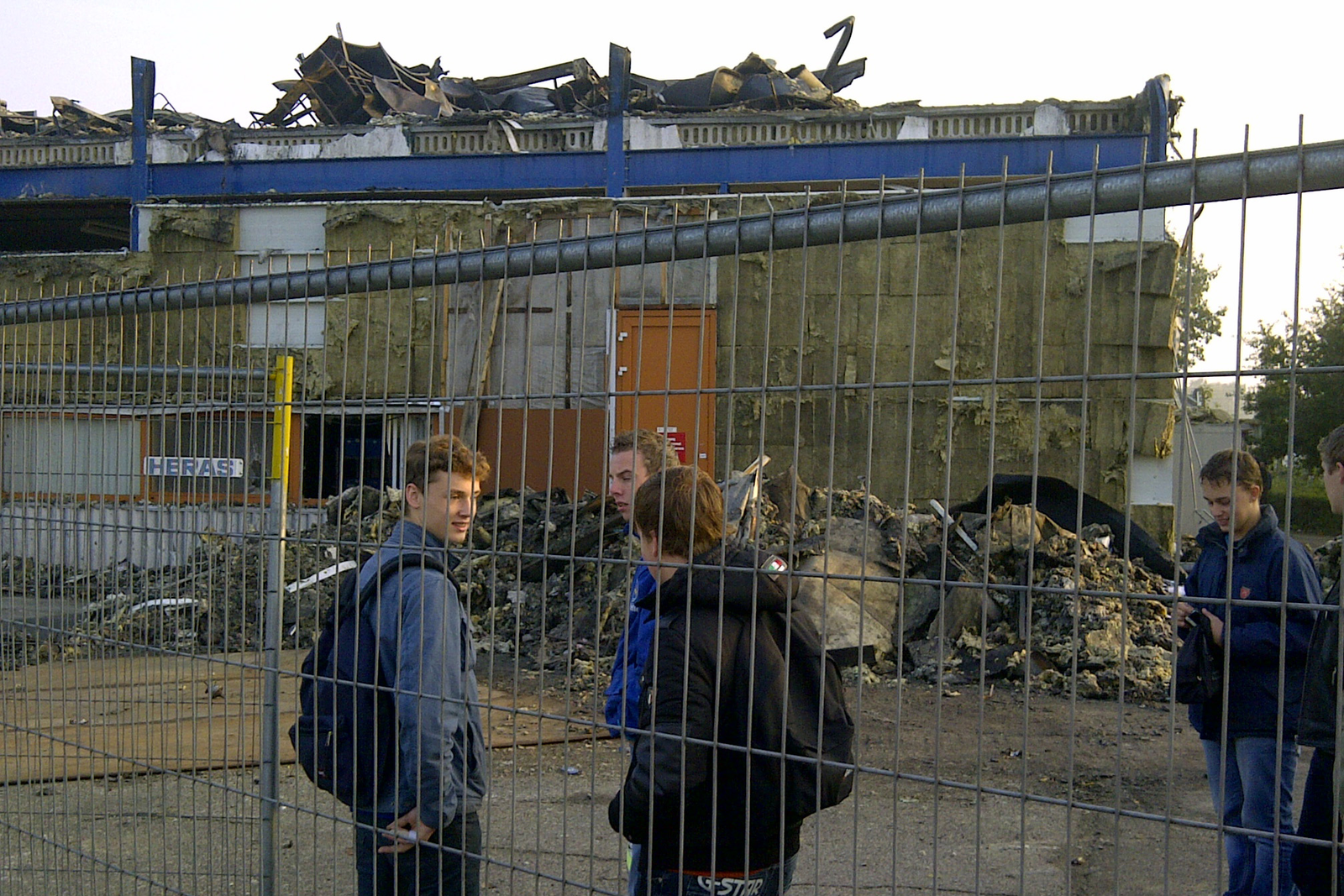 De leerlingen van de Gazelle-bedrijfsschool staan wat beduusd te kijken bij de afgebrande hal waar hun werkplek onderdeel van uitmaakt.