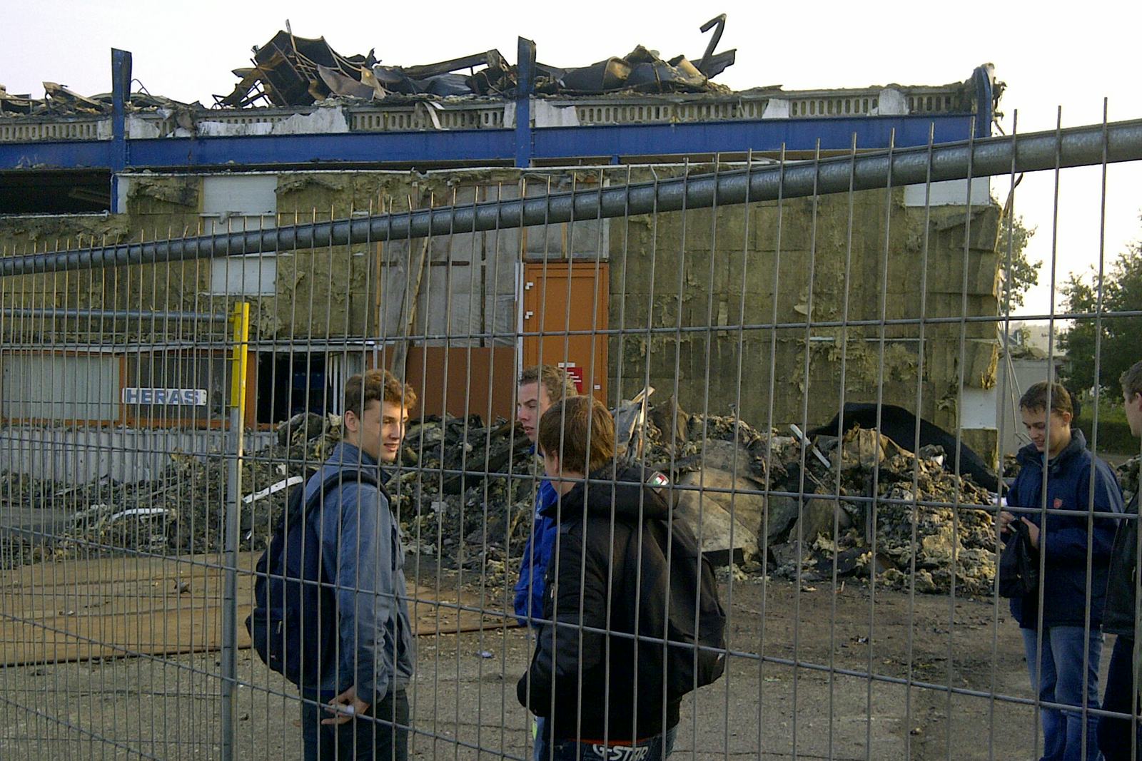 De leerlingen van de Gazelle-bedrijfsschool staan wat beduusd te kijken bij de afgebrande hal waar hun werkplek onderdeel van uitmaakt.