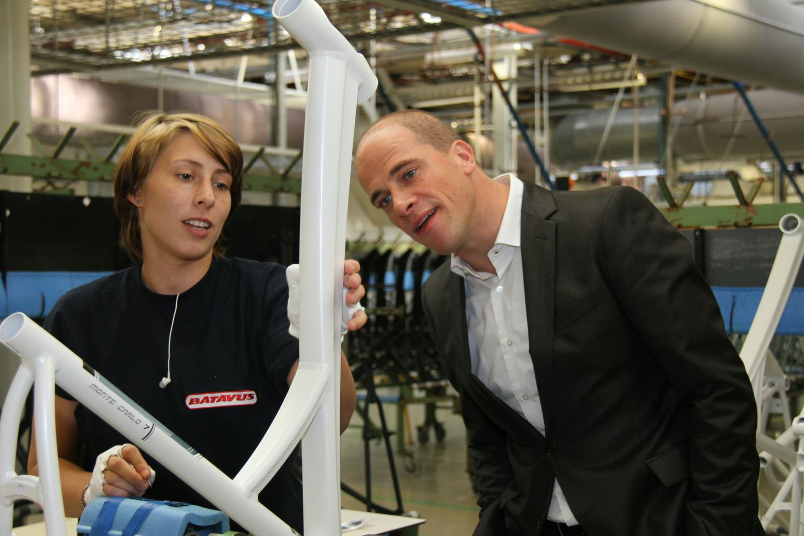 Diederik Samsom kijkt geïnteresseerd naar het aanbrengen van transfers op de framebuis.