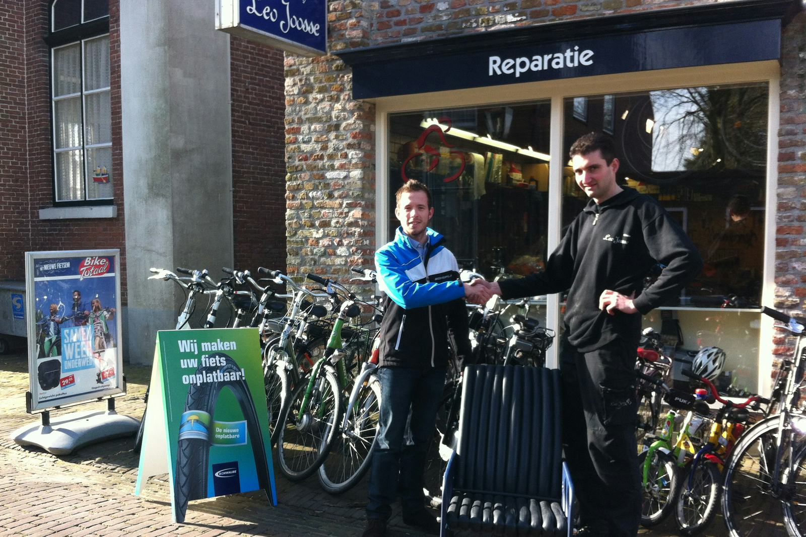 Bart van den Akker van Schwalbe reikt de gewonnen Schwalbe loungestoel uit aan een medewerker van Bike Totaal Leo Joosse (rechts).